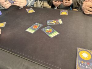 Jeu de cartes coloré de société, personne jouant à un jeu de cartes stratégique, ambiance conviviale dans un espace intérieur, souvenirs de séance de jeux entre amis, stratégie et divertissement.