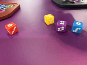 Jetons colorés de jeu de société sur surface violette, utilisé dans des jeux de stratégie ou de rôle, avec des motifs hexagonaux, parfaits pour stimuler la réflexion et l'amusement.