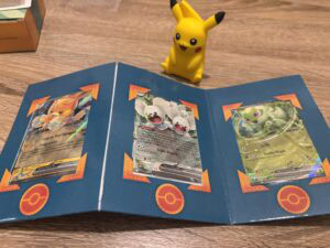Pokémon cartes Pokémon ex avec Pikachu, Méga Gardevoir et Méga Racaillou dans un portefeuille de collection, symbole de passion pour le gaming et le commerce de cartes Pokémon.