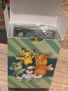 Pikachu, Évoli, et autres figurines Pokémon en figurine de collection dans une boîte de jeu Pokémon, illustrant un univers de jeux vidéo Pokémon pour fans et collectionneurs.