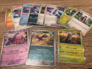 Cartes Pokémon et boosters de cartes à jouer répartis sur une surface en bois, mettant en avant la collection et le jeu de cartes Pokémon.