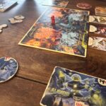 Calque de jeu de société "Air-Gaming" avec des personnages et des cartes de jeu inspirés de l'univers des jeux vidéo et des jeux de stratégie, sur une table en bois.