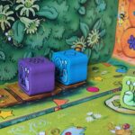 Colorful game pieces with snail illustrations on a vibrant, animated board game scene for children, featuring playful, cartoon-style art and bright colors.