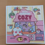 Mignon manuel dédicacé avec un design kawaii, illustrant une scène de cuisine douce et chaleureuse, parfait pour la décoration ou la collection d'objets mignons.