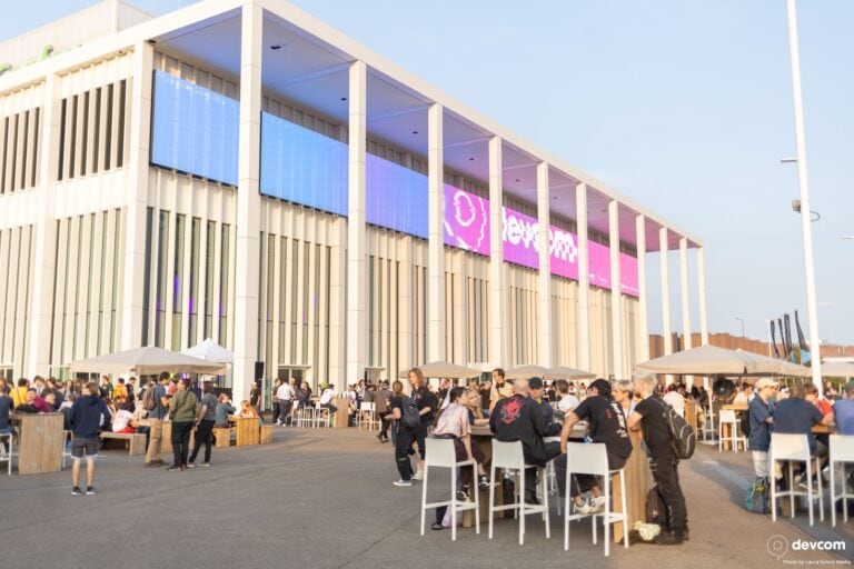 Rencontre gaming en extérieur devant un bâtiment moderne avec écrans lumineux, ambiance digitale et communauté passionnée, événement e-sport, gaming live, lieu de rassemblement gaming, accès Wi-Fi haute vitesse.