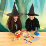 Amusements d'enfants en mode sorcellerie avec des jeunes filles portant des chapeaux de sorcière, expérimentant la science magique et la fabrication de potion dans un décor féerique.