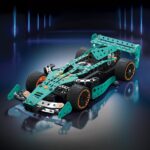 Voiture de course en modèle réduit en construction avec des pièces en plastique vert et noir, sur fond noir avec un éclairage bleu néon.