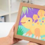 Dessin enfantin de dinosaure coloré dans une boîte en carton, illustration ludique et pastel pour l'éveil.