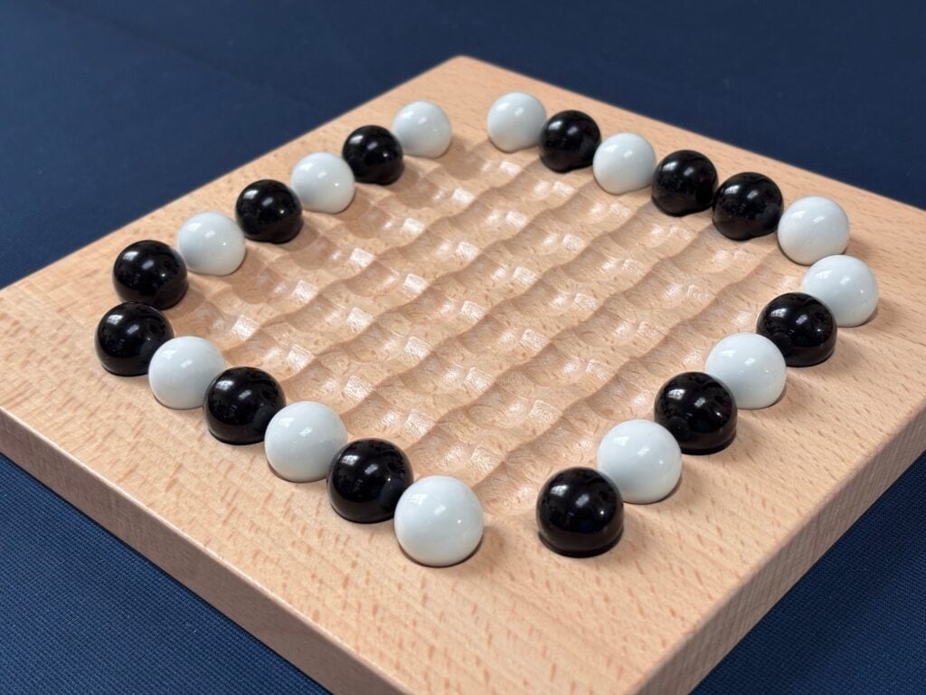 Plateau de jeu de Carrom avec palets noirs et blancs sur une surface en bois, idéal pour les amateurs de jeux de société et de stratégie.