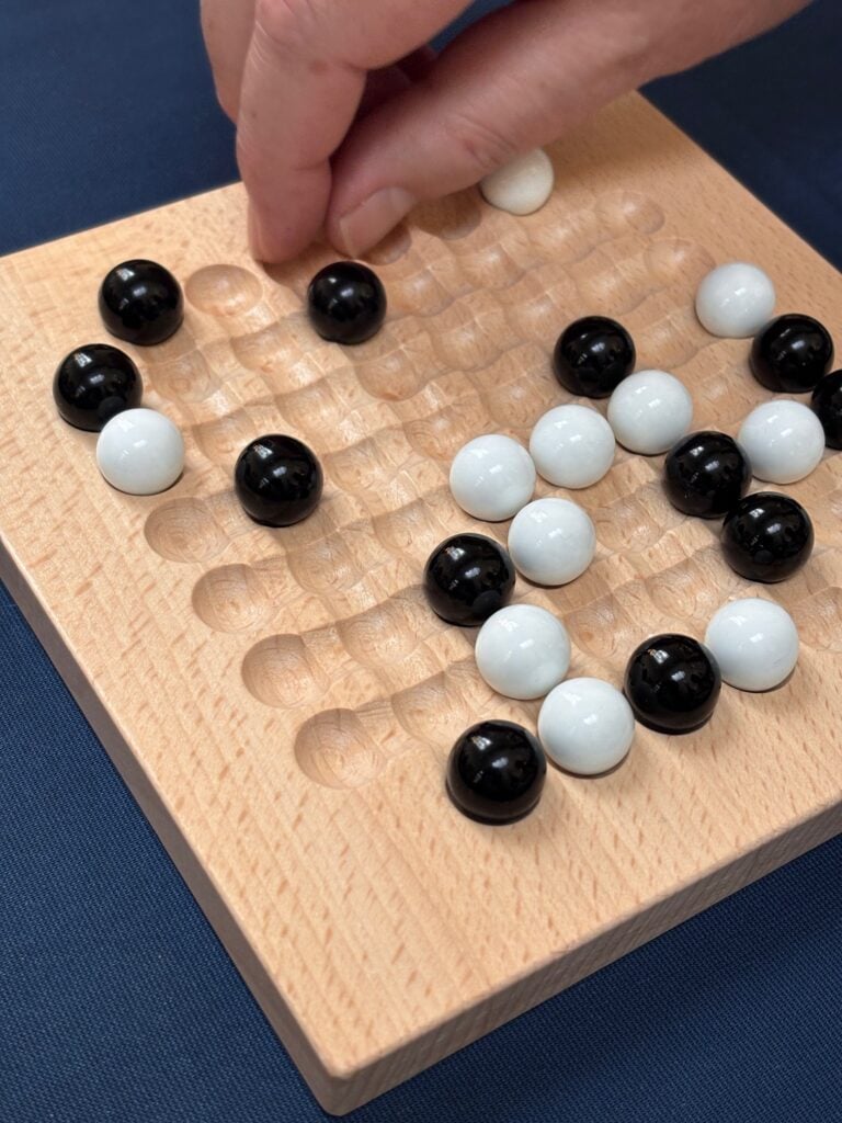 Plateau de jeu de stratégie avec pierres noires et blanches, parfait pour un jeu de go ou autres jeux de réflexion, illustration d'activité ludique et cérébrale.