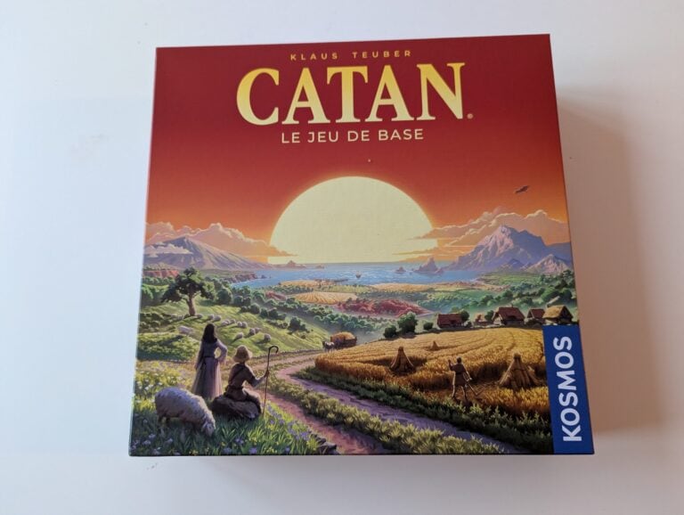 Jeu de société Catan avec paysage rural, montagne et mer au coucher du soleil, idéal pour les amateurs de divertissement convivial et stratégique.