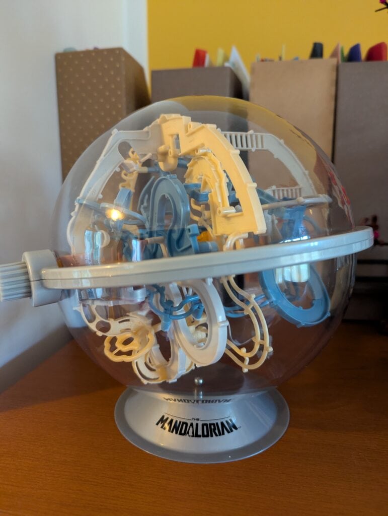 Jeu de construction de la série Mandalorian, featuring un casque en plastique transparent avec des éléments bleus et jaunes, idéal pour les fans de jeux et de collections.