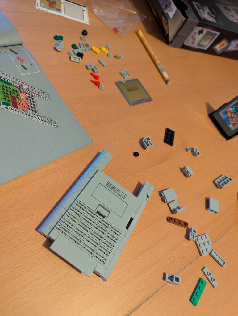 2. Vue d'ensemble d'une table avec des pièces LEGO, une instruction, une manette, et des jeux vidéo pour une expérience de jeu LEGO immersive.
