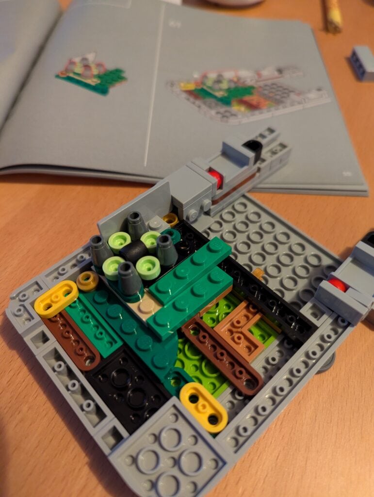 Une maquette LEGO de voiture ou d'engin mécanique en construction avec des éléments colorés et détaillés.