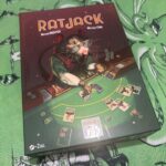 Jeu de cartes de stratégie avec un rat joueur, bonsis, et jetons de poker représentant l’univers ludique.