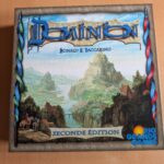 Photo du jeu de société Dominion, montrant la boîte avec illustration de paysages médiévaux et château.