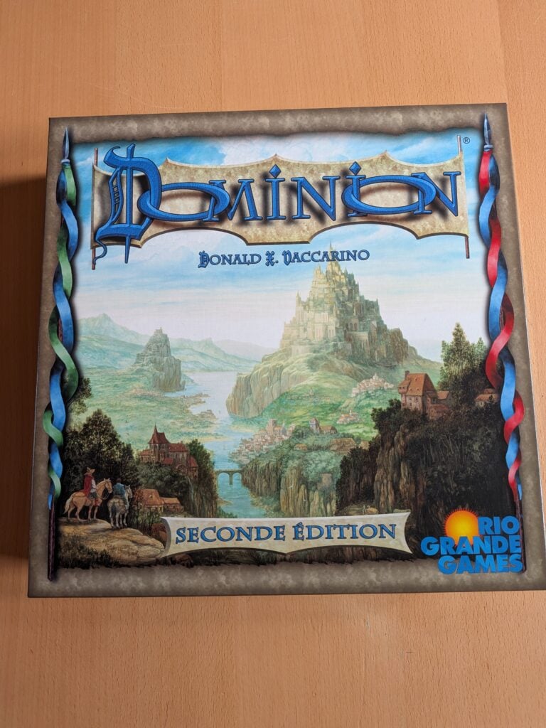 Photo du jeu de société Dominion, montrant la boîte avec illustration de paysages médiévaux et château.