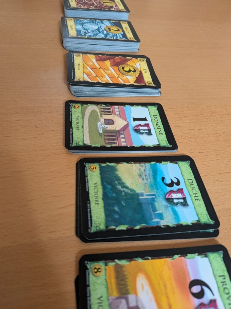 Jeu de cartes "Dominion" avec cartes colorées et illustrées, idéal pour les amateurs de jeux de société et de stratégie. Parfait pour jouer en famille ou entre amis, offrant une expérience immersive et captivante.