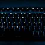 Clavier d'ordinateur rétroéclairé en mode gaming, illuminé en bleu, idéal pour jouer dans l'obscurité. Parfait pour les amateurs de jeux vidéo et de configurations de bureau modernes.