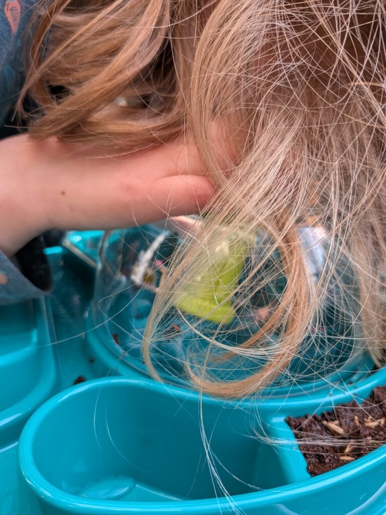Une enfant observe attentivement des insectes dans un jardin, utilisant un microscope pour étudier de près la biodiversité. L'image met en valeur l'intérêt pour la science et la nature.