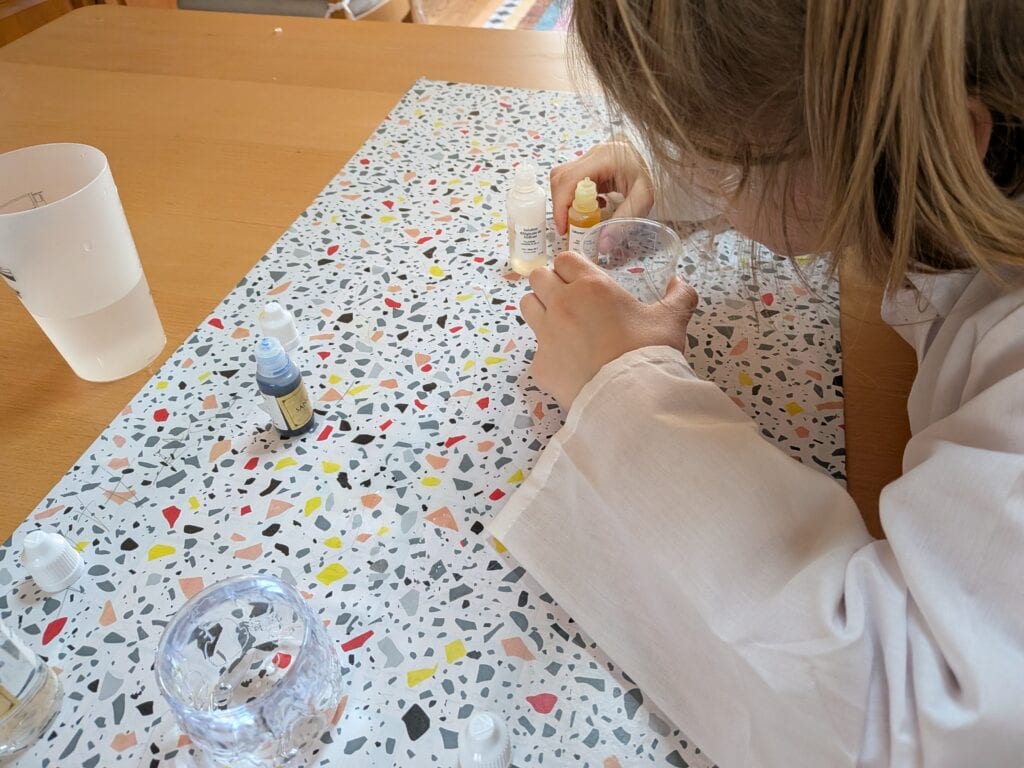 Personne préparant un produit cosmétique dans un laboratoire, avec des flacons et des ingrédients naturels, illustrant la fabrication de cosmétiques Fabulus Potium.