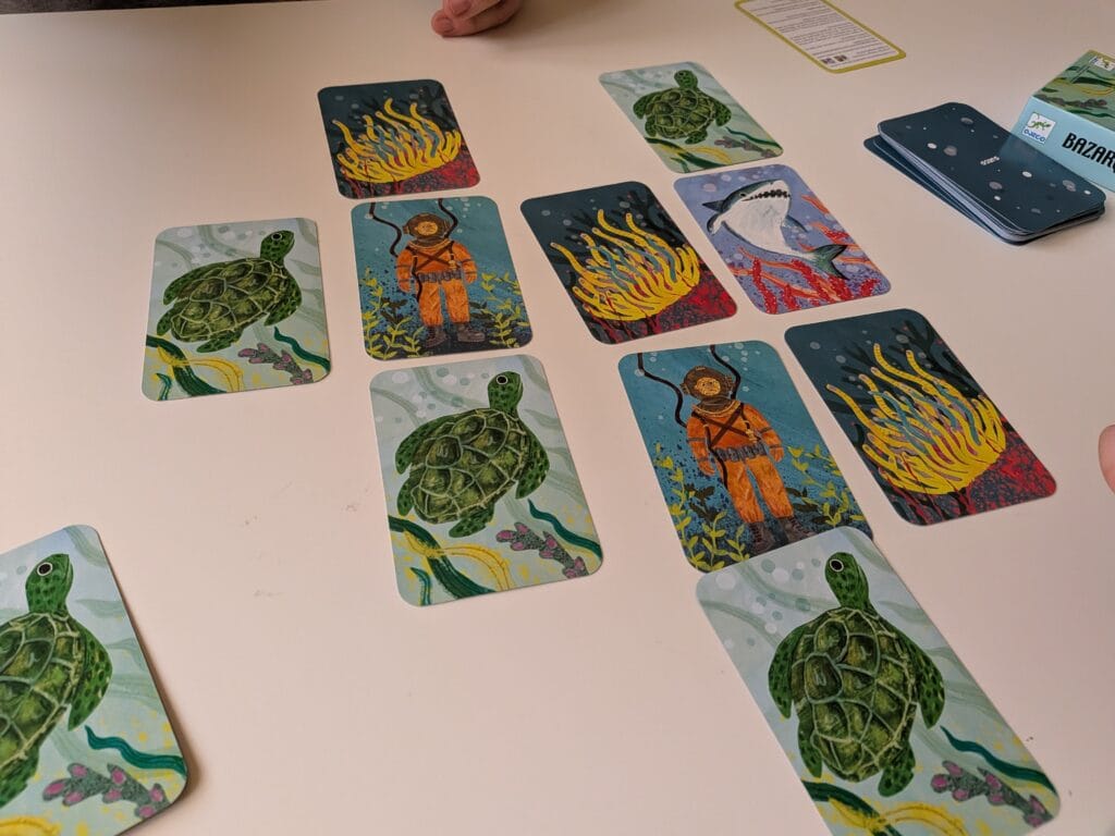 Une partie de jeu de cartes avec des illustrations de tortues, plongeurs et flammes, évoquant un thème marin et aventureux.