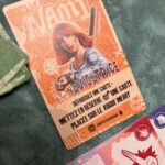 Carte de navigation Nami pour le jeu de société One Piece, illustrant la célèbre navigatrice avec un bâton, idéale pour les fans d'anime et de jeux de cartes.