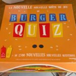 Jeu de société Burger Quiz avec boîte colorée, contenant 2700 questions pour tester vos connaissances et votre esprit d'équipe, idéal pour soirées entre amis ou en famille.