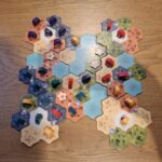 Jeu de société Les Colons de Catane avec tuiles colorées et pions sur une table en bois pour une partie stratégique.