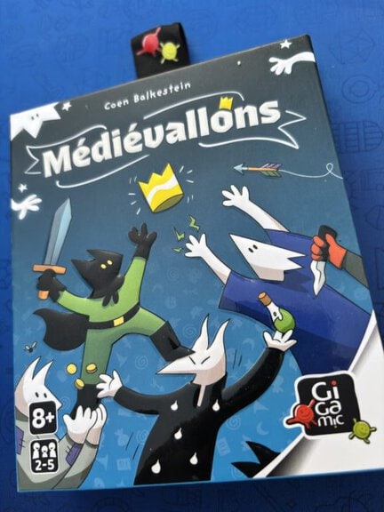 Jeu de société Médiévallons avec personnages médiévaux stylisés et éléments graphiques colorés, idéal pour les amateurs de jeux de stratégie et d'aventure.