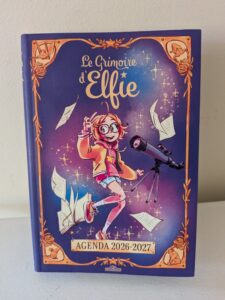 Cahier de l'agenda 2026-2027 avec illustration d'une jeune fille avec un télescope, style magique et fantastique, parfait pour organiser votre année scolaire ou personnelle.