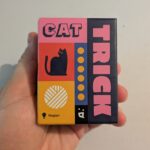 Jeu de société Trick de chat avec design coloré et illustration de chat noir, idéal pour les amateurs de jeux de société et de jeux de stratégie.
