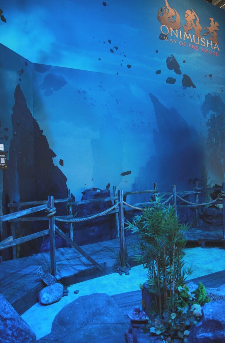 Décor immersif de l'exposition Onimusha avec un paysage japonais traditionnel et un panneau de présentation du jeu lors de la Gamescom 2026.