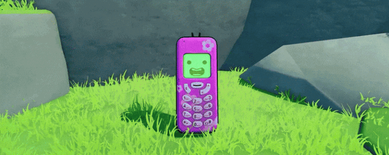 Téléphone vintage violet avec écran vert souriant, posé sur herbe verte dans un environnement naturel.
