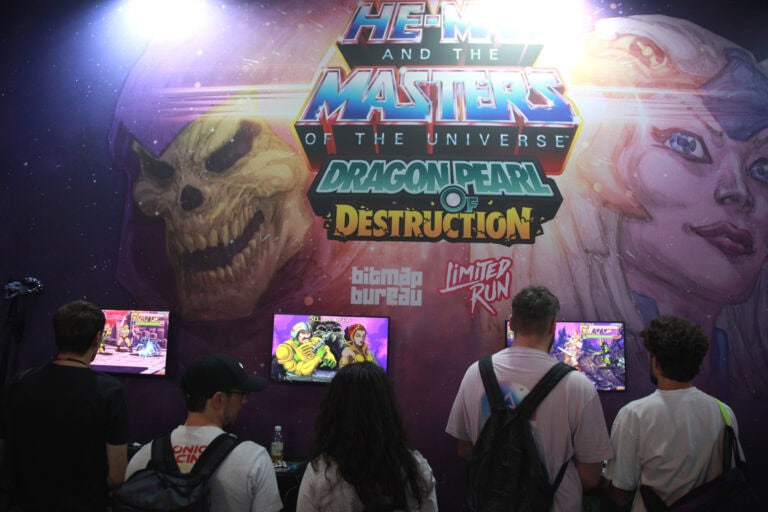 Participants jouant à des jeux vidéo lors de la Gamescom 2026, avec un grand affichage de He-Man et des personnages de Masters of the Universe.
