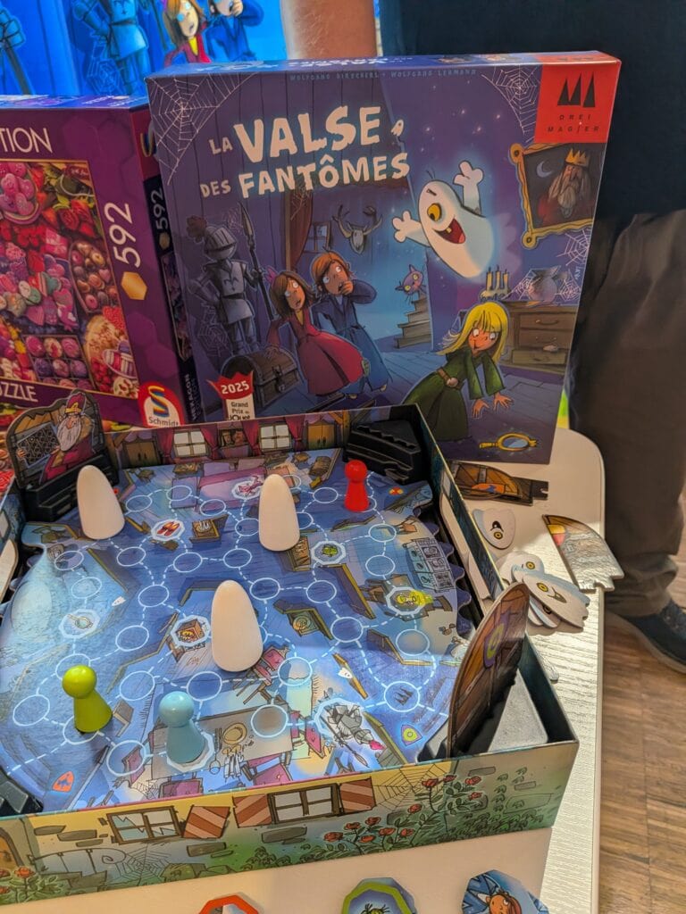 Jeu de société La Valse des Fantômes avec des figurines et un plateau illustré, présenté lors d'un événement de jeux de société.