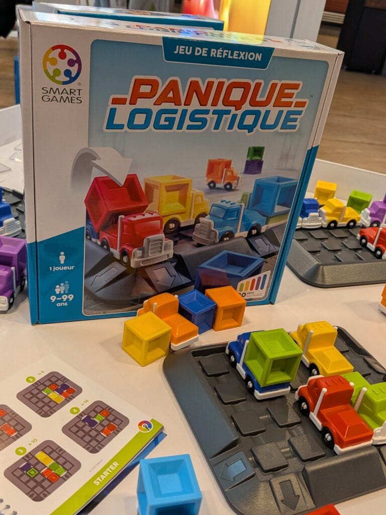 Jeu de société Panique Logistique avec des camions colorés et un plateau de jeu pour tester la logique et la planification.