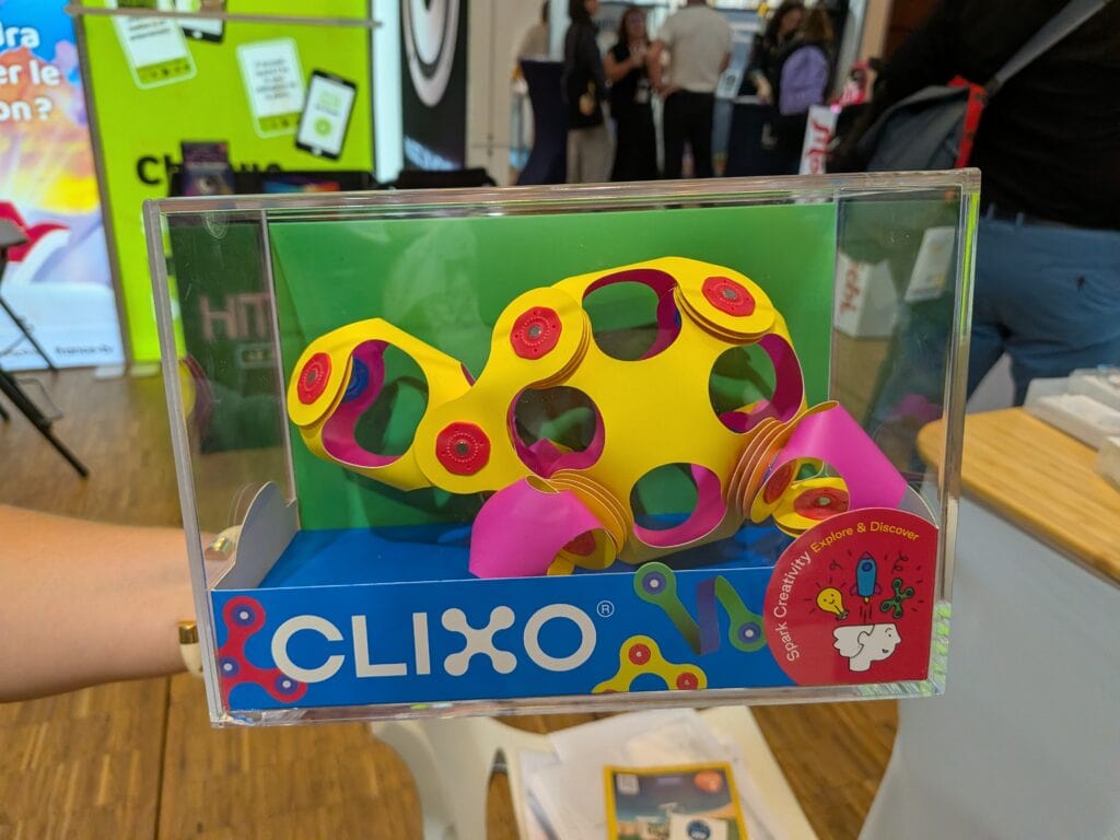 Jouet Clixo coloré en plastique jaune avec des formes modulables dans une vitrine en plastique transparent.
