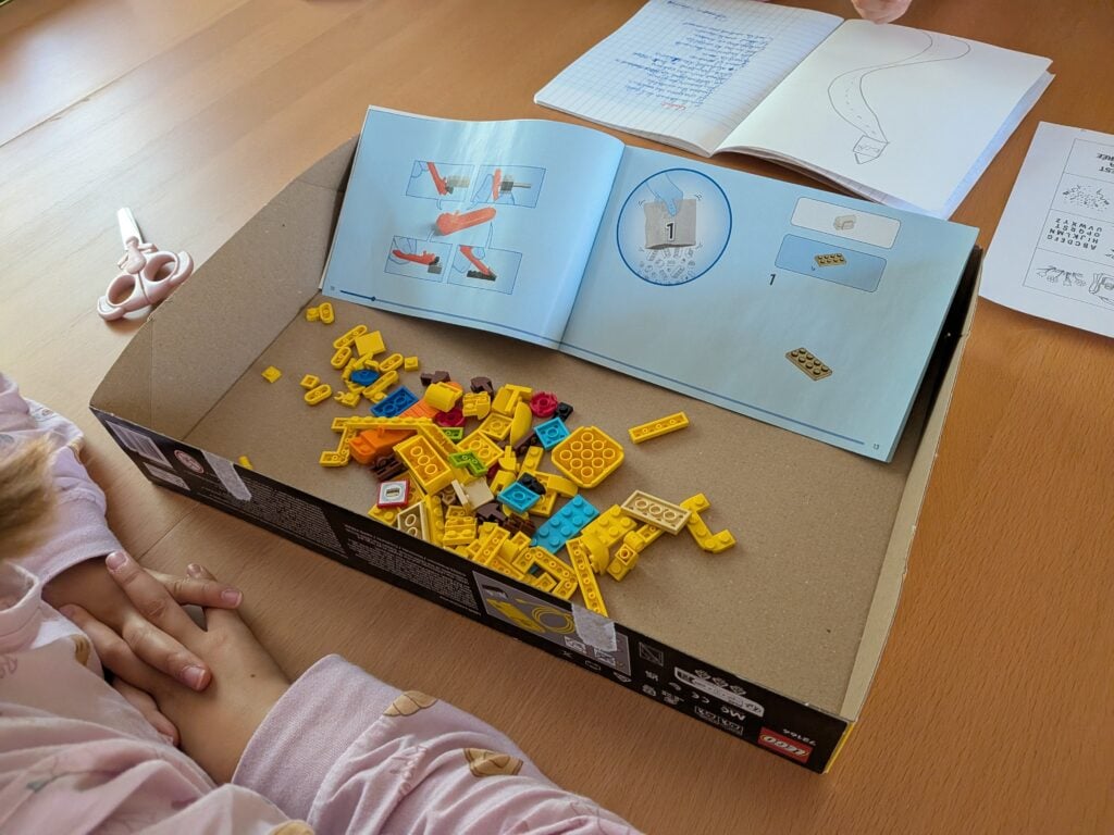 Jeune enfant construisant un LEGO Pokémon Pikachu avec des instructions et des pièces jaunes et colorées.