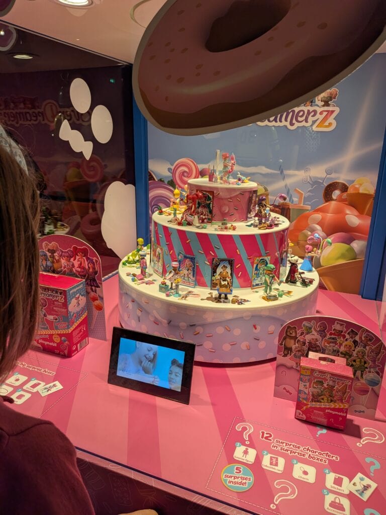 Vitrine d'une exposition Playmobil avec figurines et décorations colorées, présentation d'une collection de jouets dans un espace dédié à Drouot.