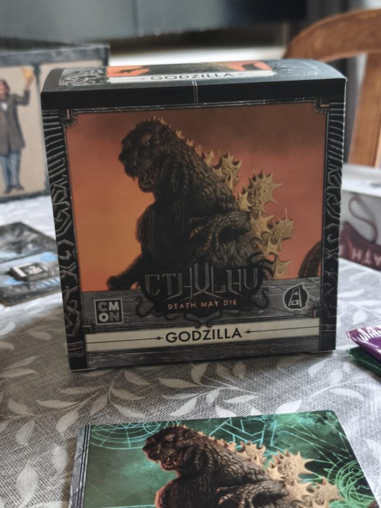 Boîte de jeu Godzilla dans l'extension Cthulhu pour Death May Die, illustrée avec Godzilla et des éléments de monstres mythiques.