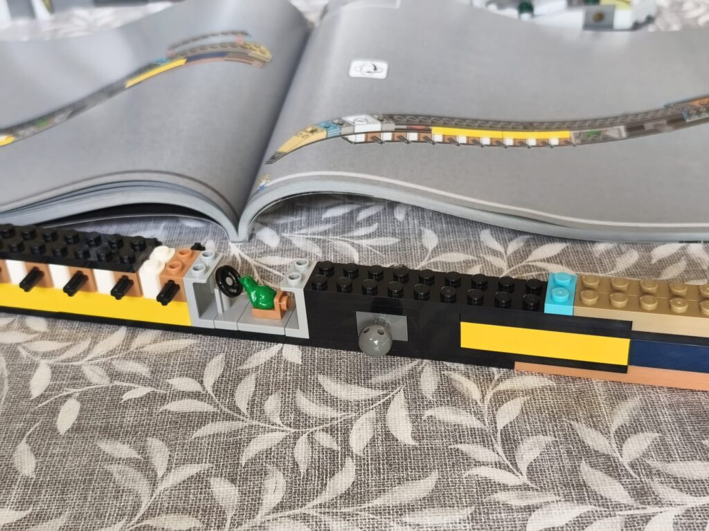 Construction LEGO d'un T-Rex en mode fossile avec détails précis et couleurs variées, posé sur un livre ouvert.