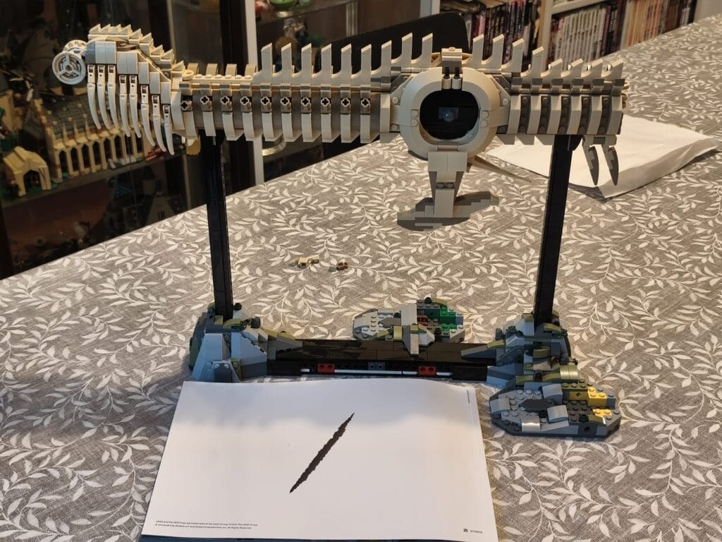 Modèle LEGO d'un Tyrannosaurus rex avec squelette détaillé, exposé sur une table avec un livre ouvert en dessous.