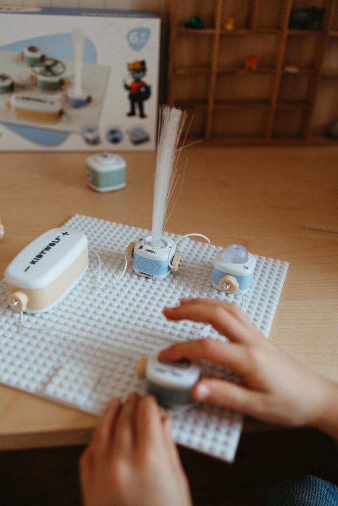 Enfant manipulant un robot éducatif avec des composants électroniques sur une table en bois.