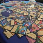 Collection de cartes de jeux de société avec illustrations colorées et textes descriptifs, sur une table bleue lors des WE MAJE DAYS.