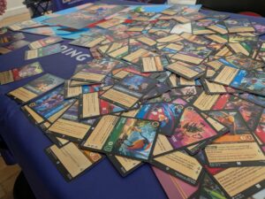 Collection de cartes de jeux de société avec illustrations colorées et textes descriptifs, sur une table bleue lors des WE MAJE DAYS.