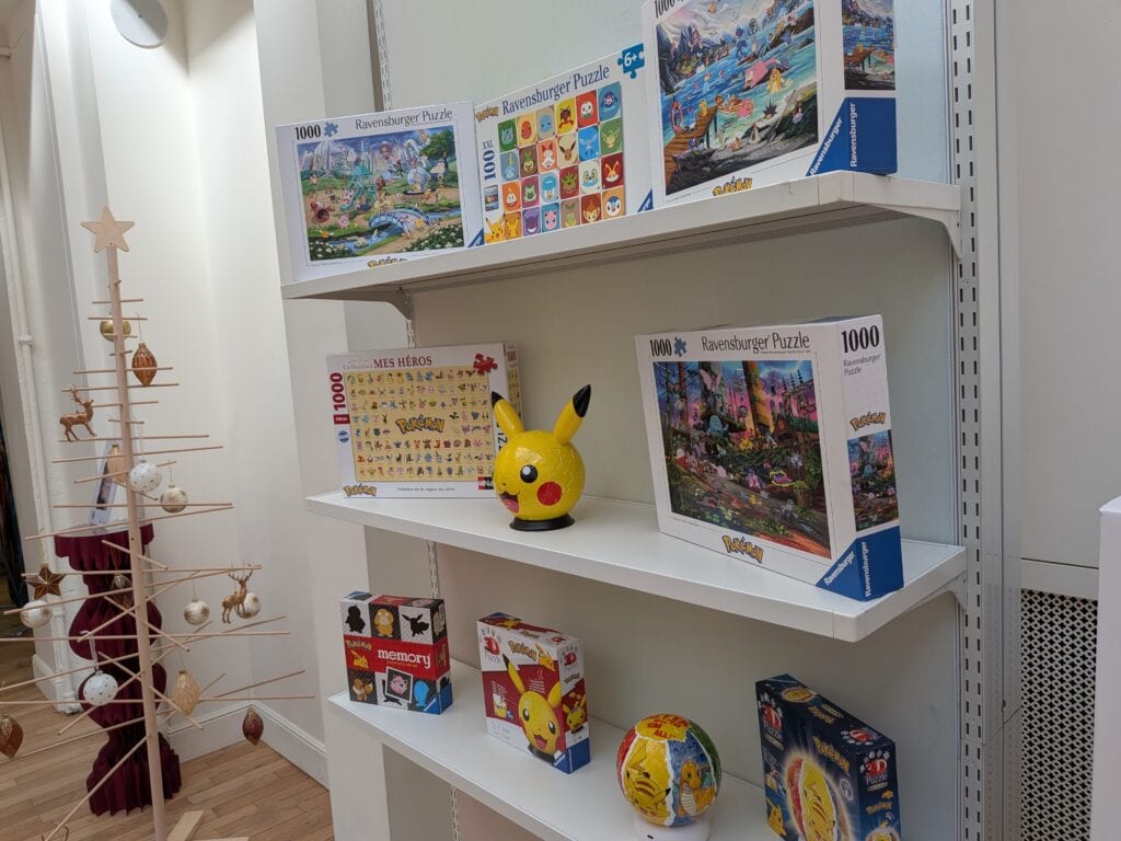 Vitrine avec puzzles Ravensburger, figurines Pokémon et jouets pour Noël 2026, mettant en avant les nouveautés de la saison.