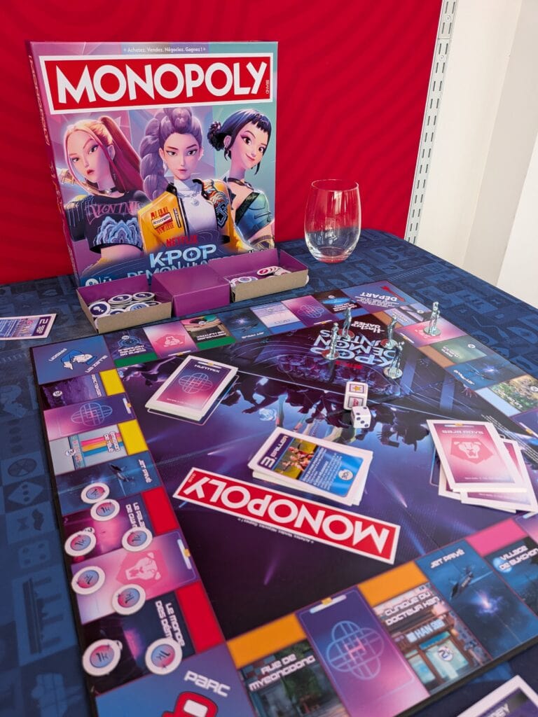 Jeu de société Monopoly K-pop avec cartes, pions et plateau sur une table, promotion pour la nouvelle édition spéciale.