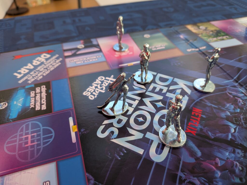 Jeu de société avec figurines en métal sur un plateau de jeu coloré, représentant une scène de stratégie et de divertissement.