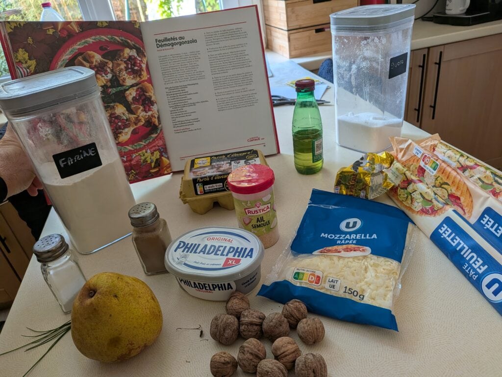 Ingrédients pour préparer un repas maison, incluant fromage, fruits, noix, et produits laitiers, sur une table de cuisine.